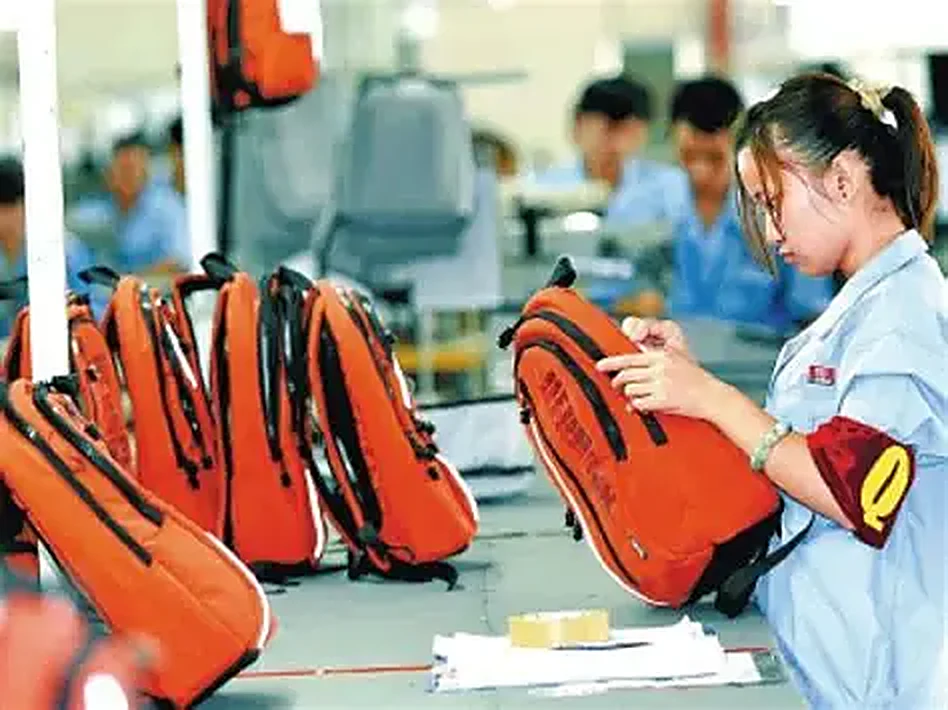 Hardside luggage shells moving along an assembly line before wheel and handle fitting